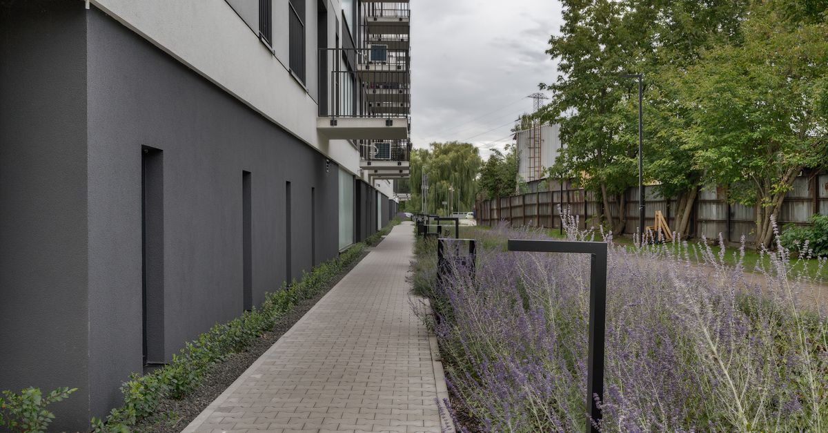 Pasillo exterior de un edificio con jardín perimetral y cañerías